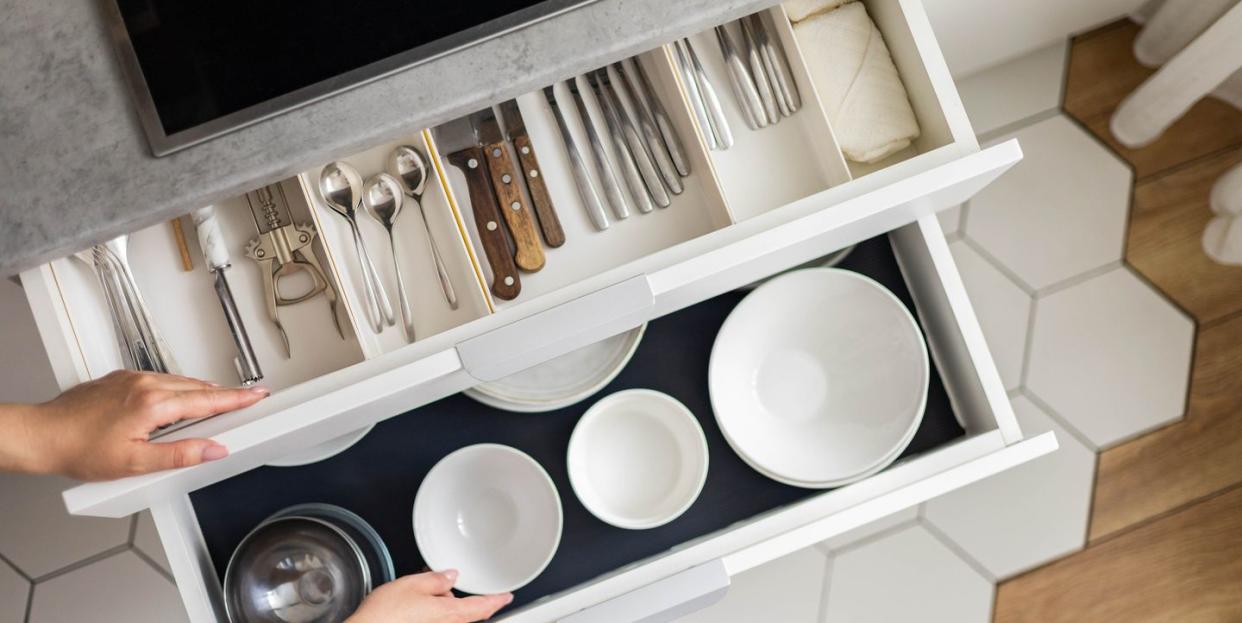 top view modern housewife tidying up kitchen cupboard during general cleaning or tidying up female neatly placing dishware and cutlery in drawer of table storage organization konmati method