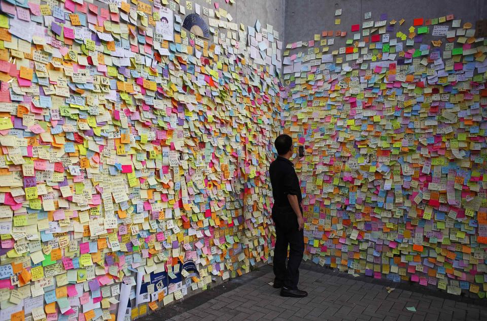 A man takes a picture on a wall full of messages left by pro-democracy protesters in Hong Kong.