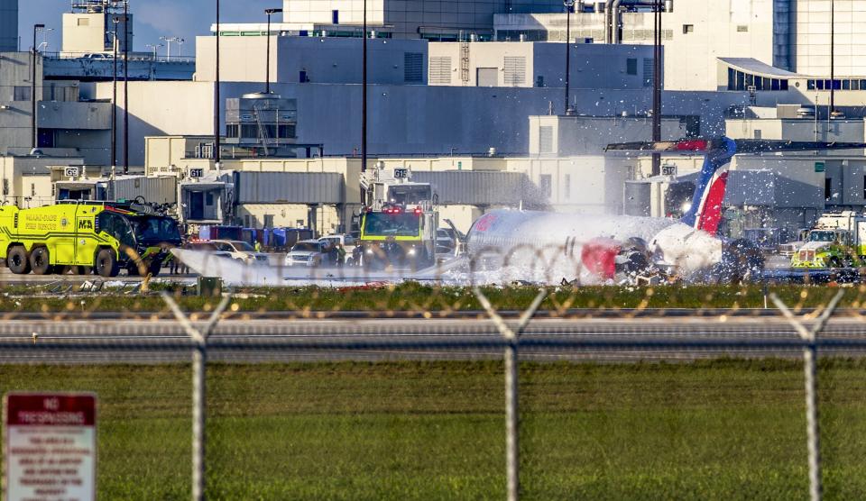 Firefighting units are seen next to a Red Air plane that caught fire after the front landing gear collapsed upon landing at Miami International Airport in Miami, after arriving from Santo Domingo, Dominican Republic, Tuesday, June 21, 2022. (Pedro Portal/Miami Herald via AP)