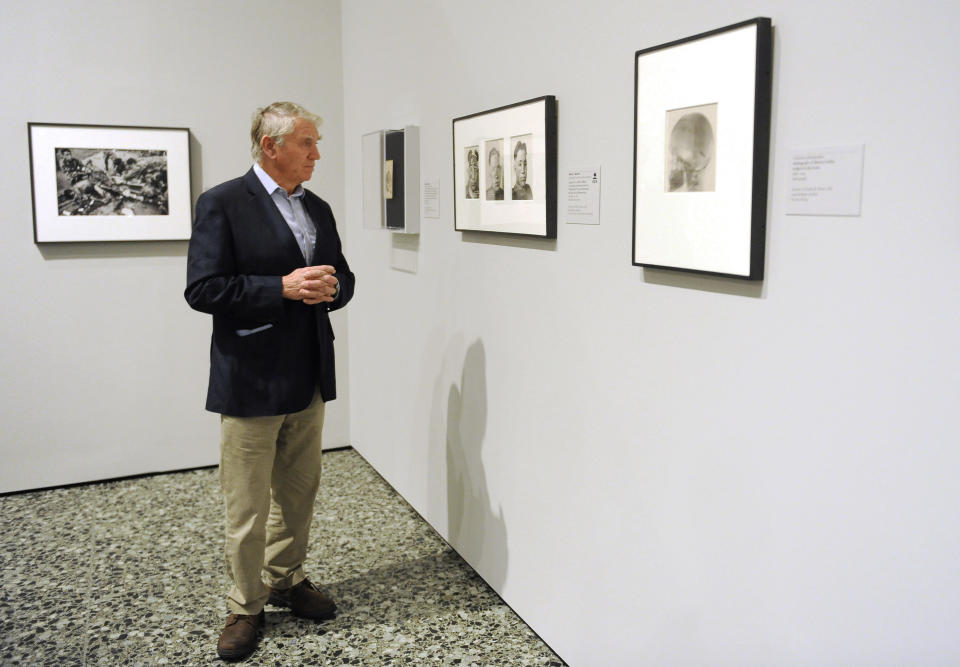 In this Thursday, Nov. 8, 2012 photo, photographer Don McCullin views some of the works in the Houston Museum of Fine Arts' war photography exhibit in Houston. The exhibit includes the work of 280 photographers from 28 nations covering the Mexican-American war in 1846 to present-day. McCullin has four photos in the exhibit. (AP Photo/Pat Sullivan)