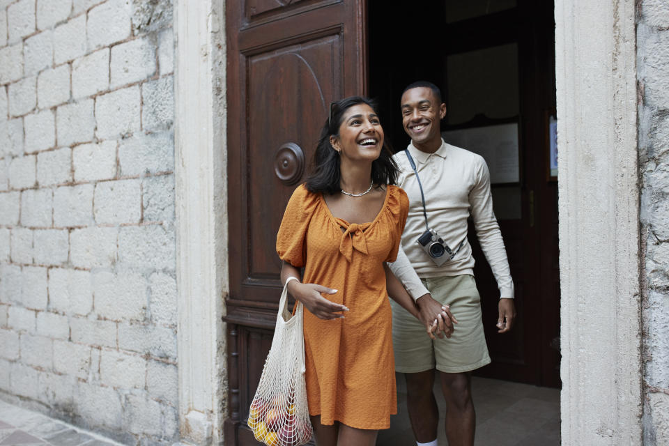 Two people smiling and walking out of a doorway, appearing happy together