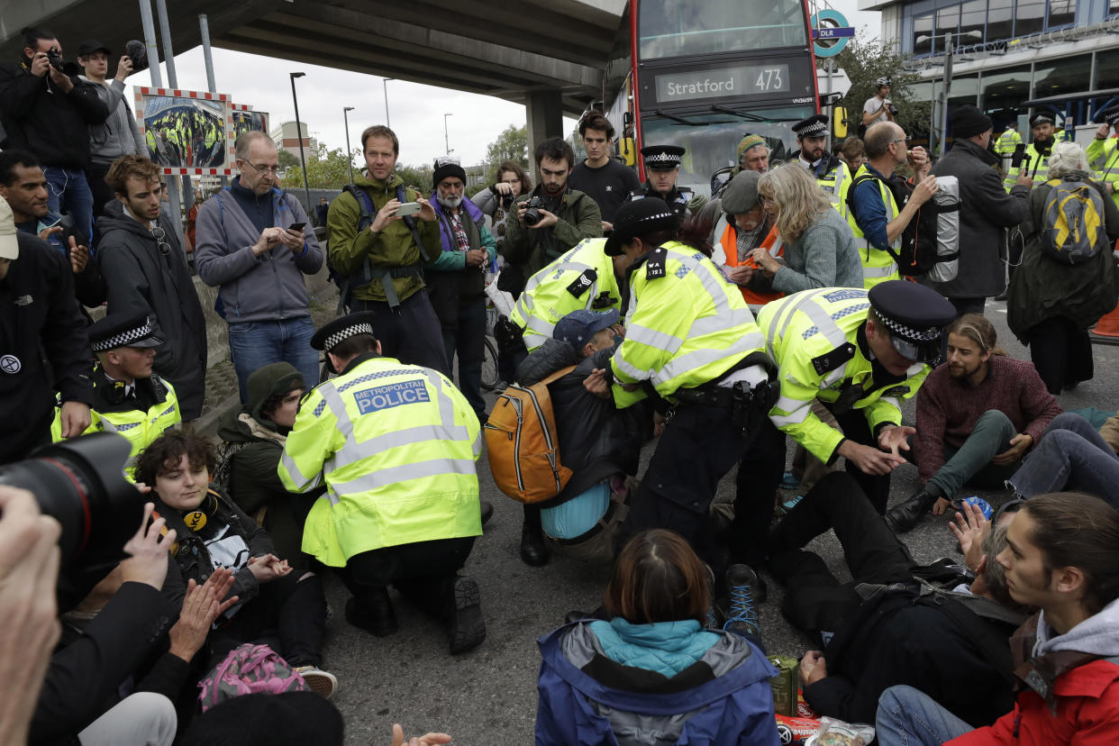 Extinction Rebellion climate change protesters block a road outside City Airport in London, Thursday, Oct. 10, 2019. Some hundreds of climate change activists are in London during a fourth day of world protests by the Extinction Rebellion movement to demand more urgent actions to counter global warming. (AP Photo/Matt Dunham)