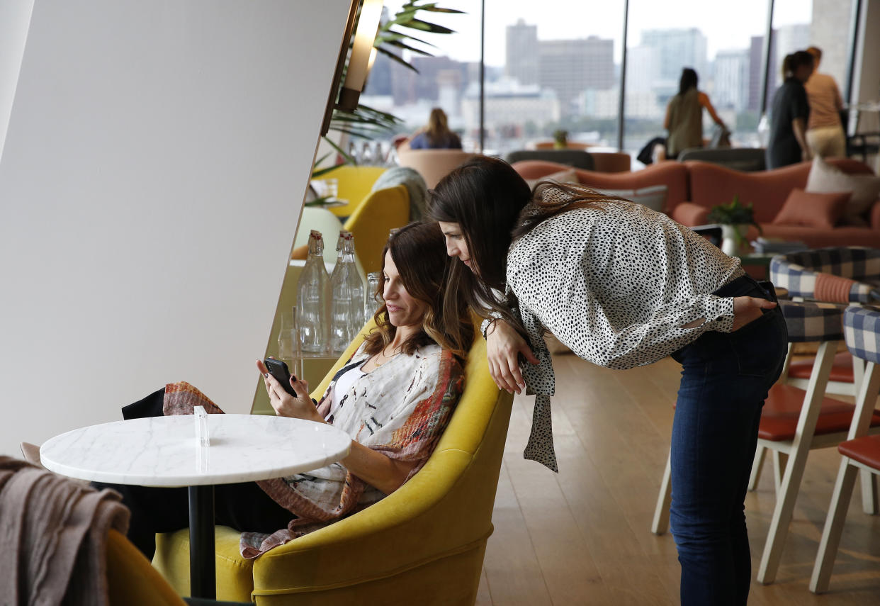 BOSTON, MA - JULY 23: Karen Cahn, Founder & CEO of iFundWomen, left, works on her phone as Kate Anderson, Co-Founder and Operations Director at iFundWomen, leans in to chat, at The Wing in Boston on July 23, 2019. The Wing is supposed to be more than a co-working space. When the first location opened in New York in 2016, the intention was to be a womens club of this era. The mission: the professional, civic, social, and economic advancement of women through community. (Photo by Jessica Rinaldi/The Boston Globe via Getty Images)