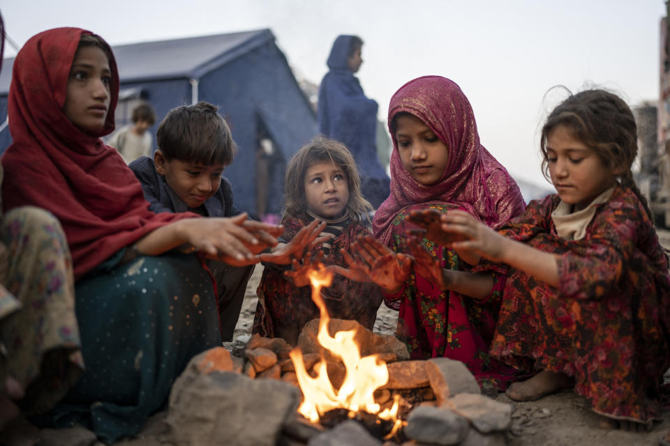 Afghan refugee children warm themselves with fire in a camp near the Torkham Pakistan-Afghanistan border in Torkham, Afghanistan, Saturday, Nov. 4, 2023. A huge number of Afghans refugees entered the Torkham border to return home hours before the expiration of a Pakistani government deadline for those who are in the country illegally to leave or face deportation. (AP Photo/Ebrahim Noroozi)