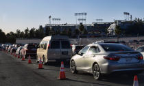 Los Angeles residents wait in line in their cars during the early morning to receive a COVID-19 vaccine at Dodger Stadium, in Los Angeles on Tuesday, Jan. 26, 2021. California is revamping its vaccine delivery system to give the state more control over who gets the shots following intense criticism of a slow and scattered rollout by counties. (AP Photo/Richard Vogel)