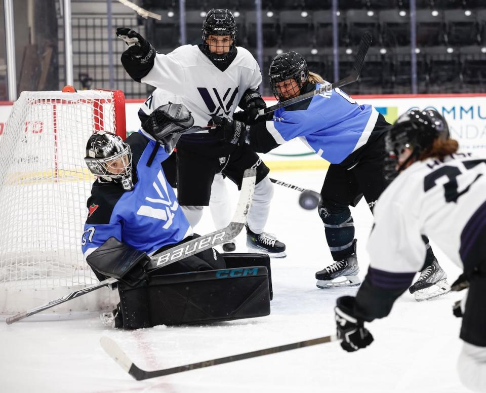 Minnesota's Taylor Heise (white jersey) battles for the puck in front of Toronto's net.