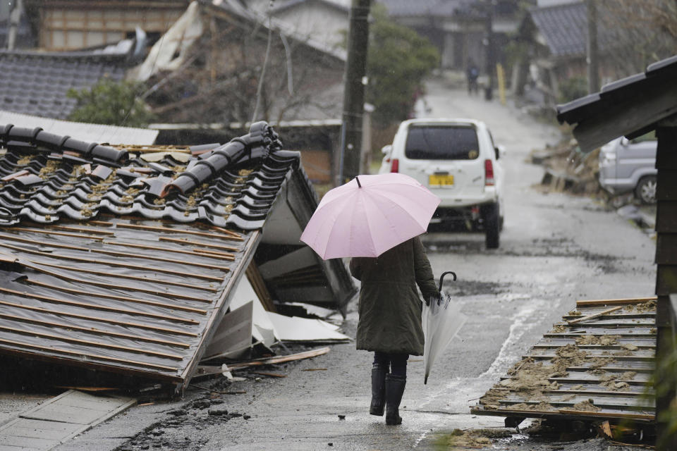 A person walks through the collapsed houses in Suzu, Ishikawa prefecture, Japan Sunday, Jan. 7, 2024. A major earthquake slammed western Japan on Jan. 1, killing scores of people, toppling buildings and setting off landslides. (Kyodo News via AP)