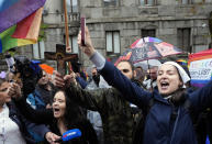 Anti-gay protesters hold icons and crosses as they stand on a large rainbow flag during the European LGBTQ pride march in Belgrade, Serbia, Saturday, Sept. 17, 2022. Serbian police have banned Saturday's parade, citing a risk of clashes with far-right activists. (AP Photo/Darko Vojinovic)