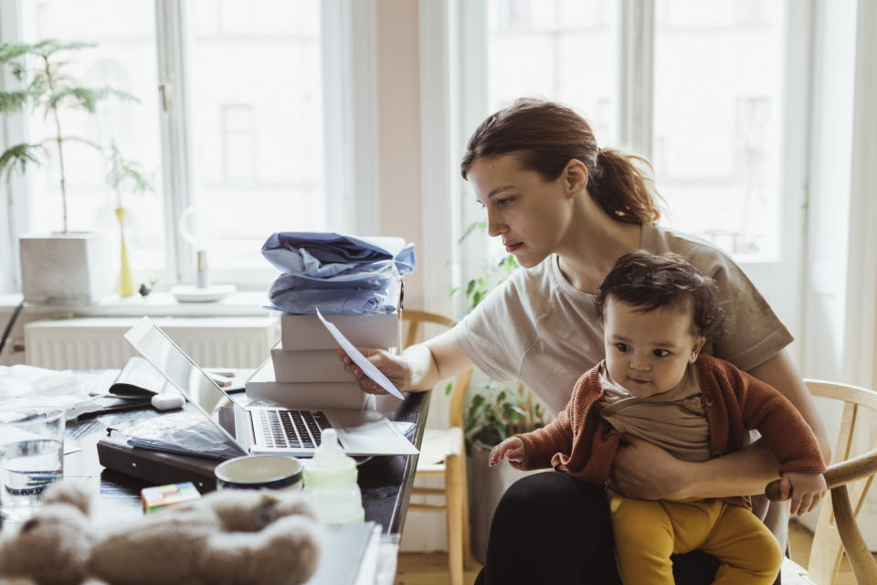 Young mom looking at bills while holding her baby