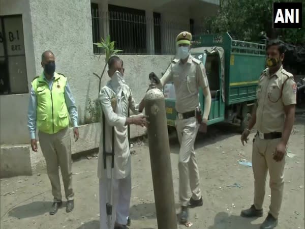 Delhi police constable helping a disabled man carrying oxygen cylinder (Photo/ANI)  