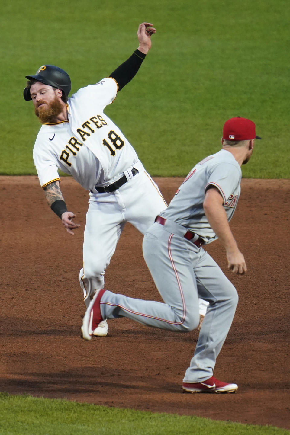 Pittsburgh Pirates' Ben Gamel (18) twists away as he tries to evade the tag from Cincinnati Reds third baseman Brandon Drury after he was caught off first and then in in a rundown between first and second during the sixth inning of a baseball game Thursday, May 12, 2022, in Pittsburgh. (AP Photo/Keith Srakocic)