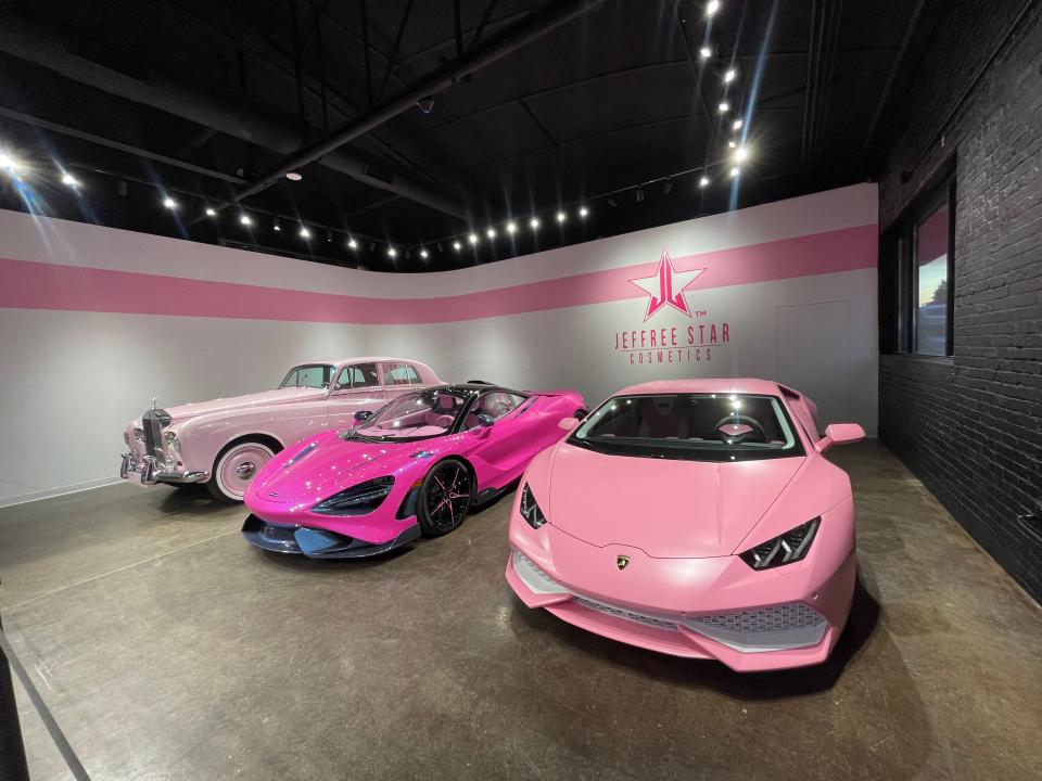 three pink cars in a showroom-style space with the Jeffree Star cosmetics logo behind them on the wall