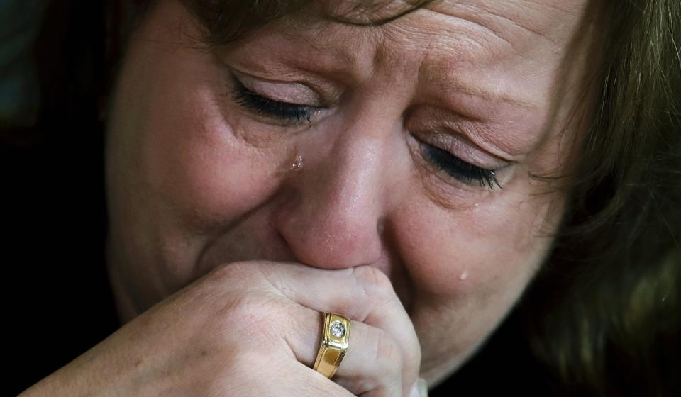 FILE - In this December 2018 file photo, Terri Osborne, a police dispatcher in Hudson, Mass., cries during a group support meeting as she talks about the loss of her son to an opioid overdose in July 2018. Reports emerging about a possible financial settlement in 2019 with Purdue Pharma, the company that has come to symbolize the nation's opioid epidemic, suggests the settlement amount won't come anywhere near what the national crisis has cost. (AP Photo/Charles Krupa, File)