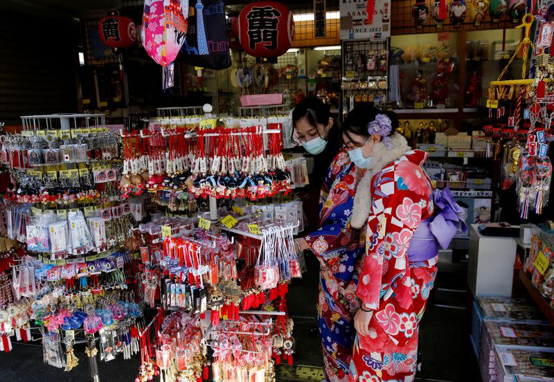 Tourists wearing Kimono and surgical masks visit a souvenir shop near Sensoji temple in Tokyo