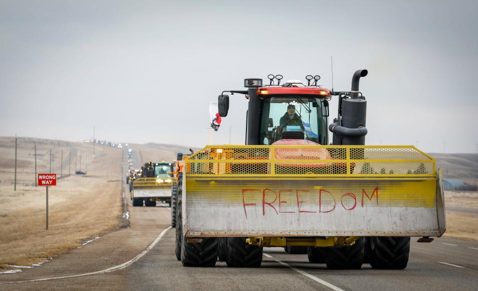 Anti-COVID-19 vaccine mandate demonstrators leave in a truck convoy after blocking the highway at the busy U.S. border crossing in Coutts, Alberta, Tuesday, Feb. 15, 2022. (Jeff McIntosh/The Canadian Press via AP) ORG XMIT: JMC109