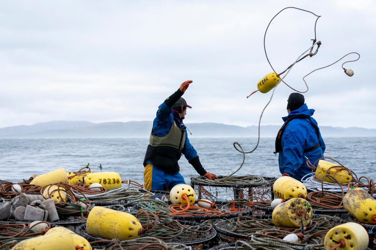 Anthony Abell (left) and Lyle Ashouwak (right) drop crab pots off the Fishing Vessel Insatiable on June 15, 2023, in Kodiak, Alaska. As the ocean temperatures rise, fishers are forced to adapt to harvesting different species.