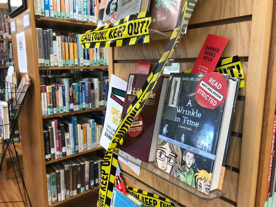 A bookshelf with caution tape marking Banned Books Week