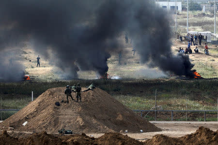 Israeli soldiers are seen next to the border fence on the Israeli side of the Israel-Gaza border, as Palestinians protest on the Gaza side of the border, Israel April 5, 2018. REUTERS/Amir Cohen