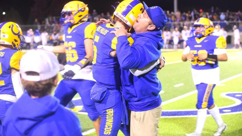 Dos Palos High School senior quarterback Peyton Van Worth (5) hugs his father Mike Van Worth after the Broncos’ 28-21 victory over Exeter in the Central Section Division IV semifinals on Friday, Nov. 17, 2023.