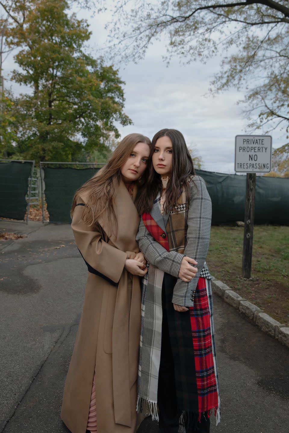 olivia and emma stand near the fenced off entrance to their family's former estate