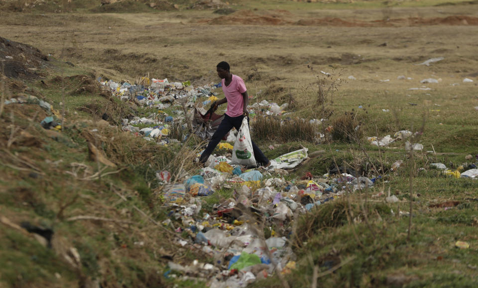 A man crosses a stream littered with plastic in the Sharpville township south of Johannesburg Monday, Sept. 14, 2020. (AP Photo/Themba Hadebe)