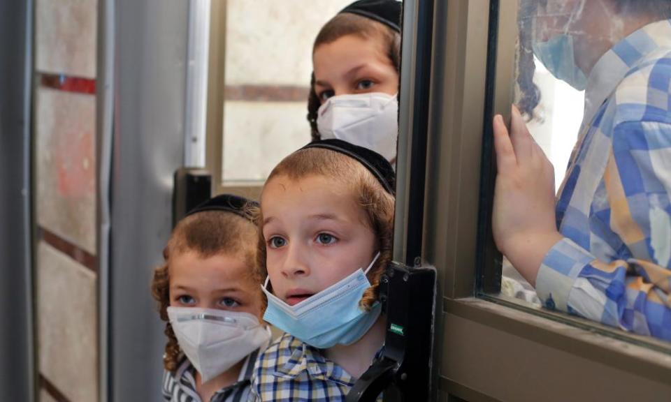 Children watch as Israeli medical workers take swab tests for Covid-19 in Rechovot, in Israel.