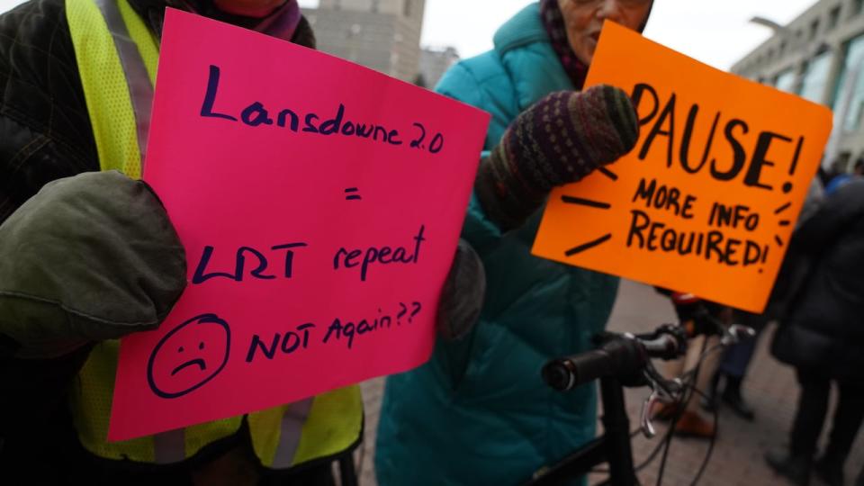 People hold signs outside Ottawa City Hall before the first day of delegations addressing Lansdowne 2.0 on Nov. 2, 2023.