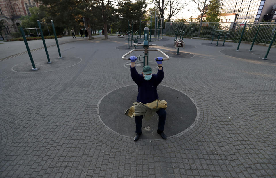 FILE - In this Friday, April 24, 2020 file photo, a man wearing a mask against the spread of the new coronavirus exercises in a park during a curfew in Belgrade, Serbia. Serbia's president Aleksandar Vucic has cancelled his party's pre-election rallies and officials in Bosnia, Macedonia and Albania are appealing on citizens to respect protection measures after relaxation of rules against the new coronavirus led to a recent spike in cases in the Balkan countries. (AP Photo/Darko Vojinovic, File)