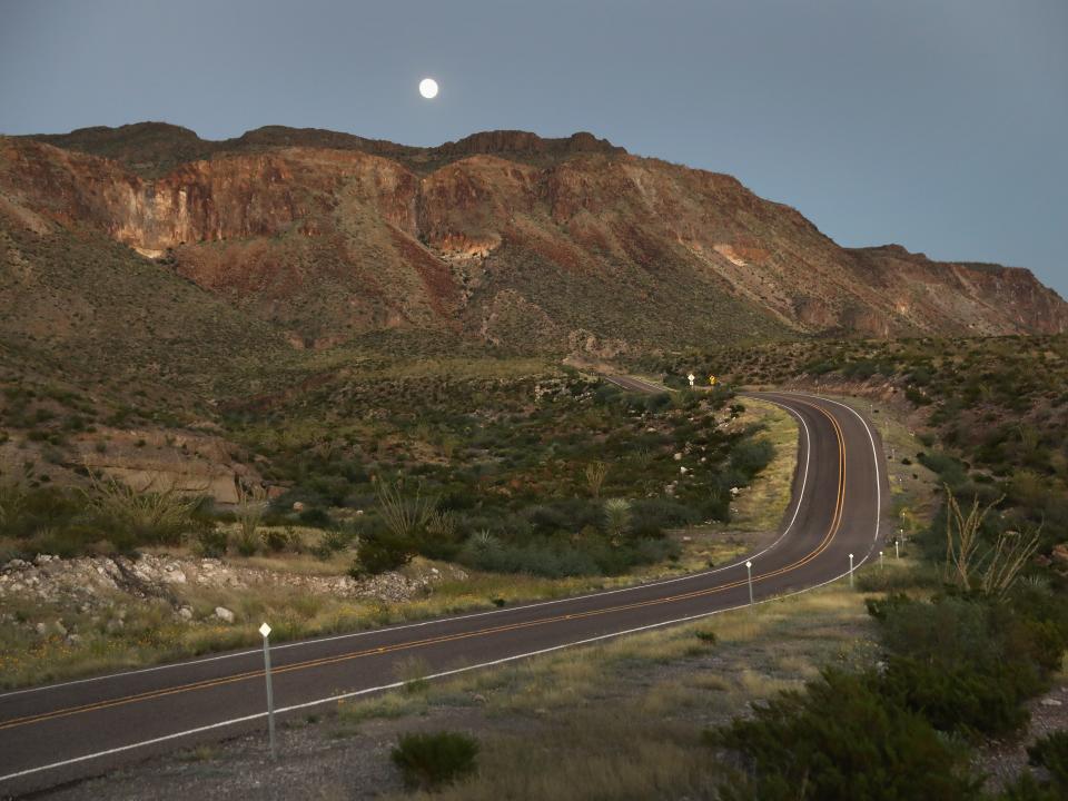 A stretch of road is seen amid an arid, sloping landscape.