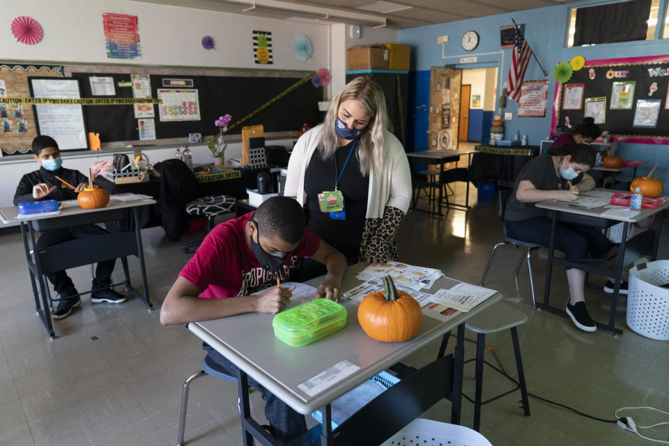 Marissa De Gaetano, center, looks over a student's shoulder as she teaches a class with students who are autistic during the coronavirus outbreak at Roosevelt High School - Early College Studies, Thursday, Oct. 15, 2020, in Yonkers, N.Y. (AP Photo/Mary Altaffer)