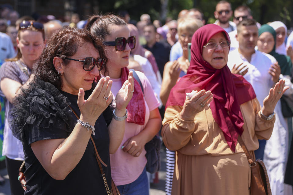 Women pray in Sarajevo, Bosnia, Sunday, July 9, 2023 next to a truck carrying 30 coffins with remains of the recently identified victims of the 1995 Srebrenica genocide. So far, the remains of more than 6,600 people have been found and buried at a vast and ever-expanding memorial cemetery in Potocari, outside Srebrenica. (AP Photo/Armin Durgut)