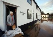 TAUNTON, UNITED KINGDOM - NOVEMBER 25: Anne Bartlett and her dog Henry look out from their flooded property in the centre of the village of Ruishton, near Taunton, on November 25, 2012 in Somerset, England. Another band of heavy rain and wind continued to bring disruption to many parts of the country today particularly in the south west which was already suffering from flooding earlier in the week. (Photo by Matt Cardy/Getty Images)