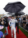 NASCAR Cup Series points leader Kyle Larson, center, walks to a track meeting as rain falls before a NASCAR Cup Series auto race at Kansas Speedway in Kansas City, Kan., Sunday, May 5, 2024. (AP Photo/Colin E. Braley)