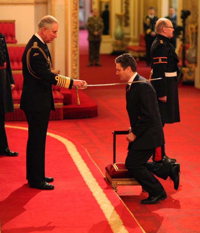 Sir Keir kneels as he is invested as a Knight Commander of the Order of the Bath by the then-Prince of Wales
