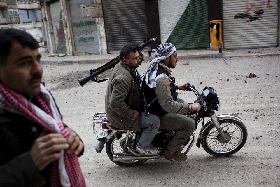 <p>Free Syrian Army fighters ride a motorbike to approach Syrian Army tanks in Idlib, northern Syria, on March 11, 2012. (Photo: Rodrigo Abd/AP) </p>