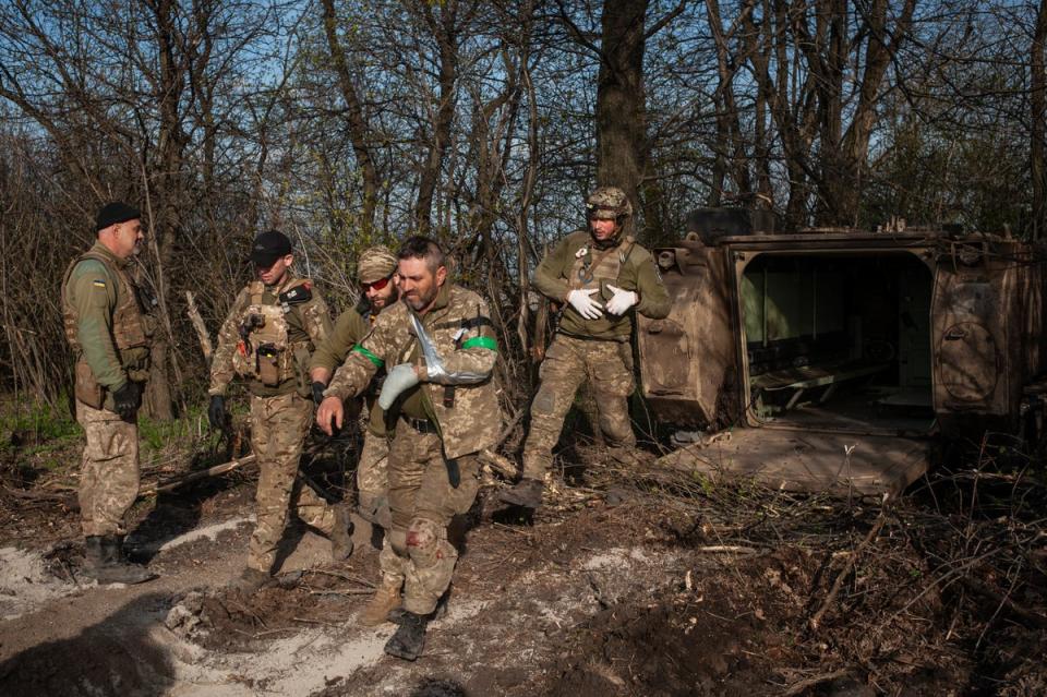 Military medics help a soldier wounded in a battle to get into an evacuation vehicle near Bakhmut, Donetsk region, Ukraine, Monday, 10 April 2023 (AP)