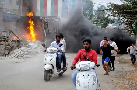 Men make their way past a burning lorry in Bengaluru, India September 12, 2016. REUTERS/Abhishek N. Chinnappa/File Photo