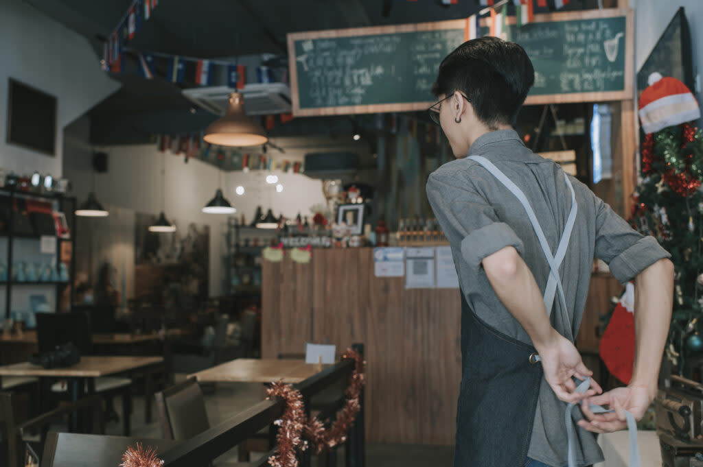 A teen worker ties his apron