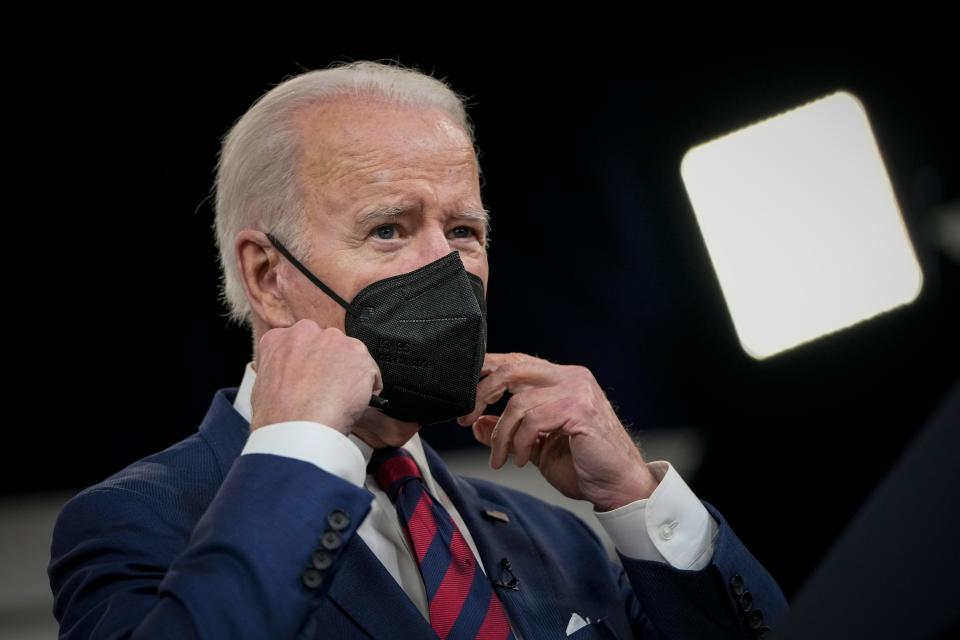 US President Joe Biden prepares to remove his face mask at the White House complex on December 23, 2021 in Washington, DC.