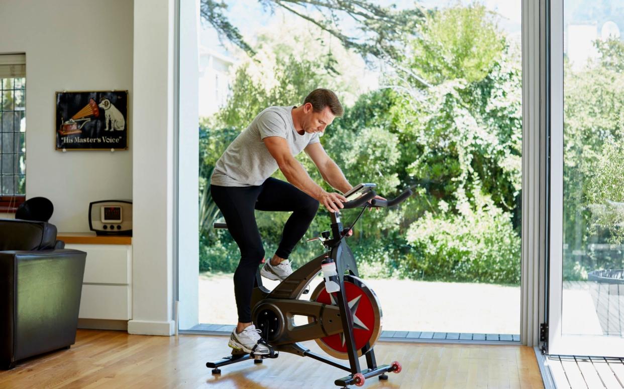 Man working out on exercise bike at home - Digital Vision