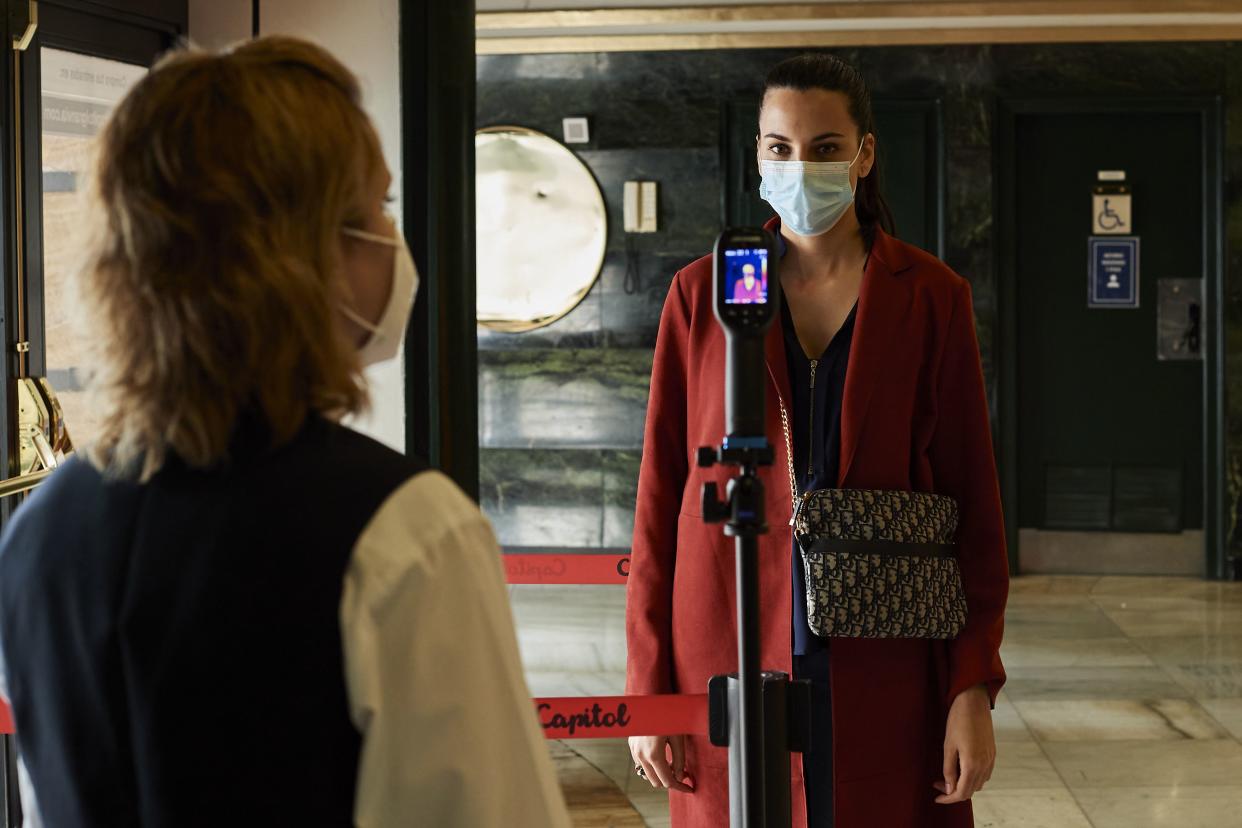 A customer wearing a face mask has her temperature measured at the entrance of the reopened Capitol cinema on June 12, 2020 in Madrid, Spain.