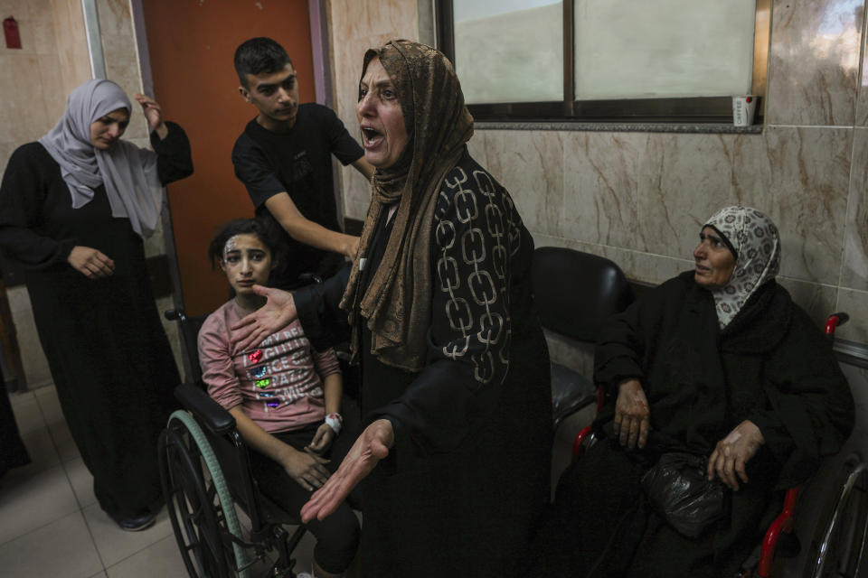 A Palestinian woman reacts next to people wounded in an Israeli airstrike, at al-Aqsa Hospital in Deir el-Balah, central Gaza Strip, Sunday, Oct. 15, 2023. (AP Photo/Adel Hana)