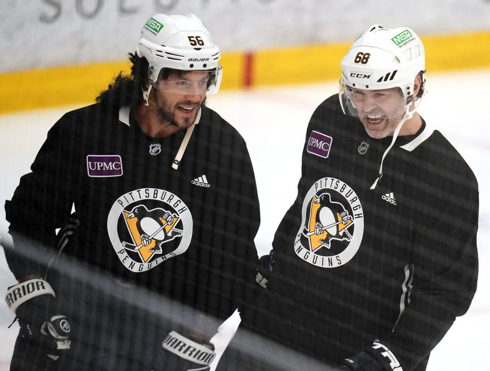 Pittsburgh Penguins' Kris Letang, left, wearing a mullet wig, shares a laugh with former Penguins player Jaromir Jagr during NHL hockey practice, Saturday, Feb. 17, 2024, in Cranberry, Pa. Jagr, who spent 11 seasons playing for the Penguins, will have his No. 68 officially retired during a pre-game ceremony before an NHL hockey game between the Los Angeles Kings and Penguins on Sunday. (AP Photo/Gene J. Puskar)