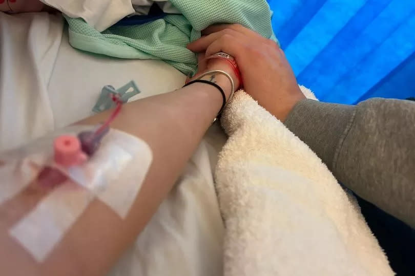 Grace Almey in hospital holding her boyfriend's hand