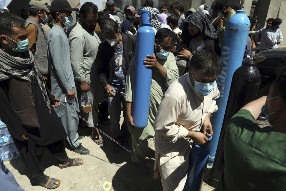 A man carries an oxygen cylinder from a privately owned oxygen factory, in Kabul, Afghanistan, Saturday, June 19, 2021. Health officials say Afghanistan is fast running out of oxygen as a deadly third surge of COVID worsen. (AP Photo/Rahmat Gul)