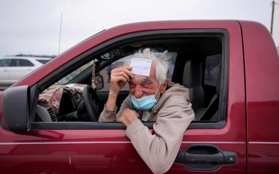 Taras Mychalewych, 75, poses for a portrait with his vaccination card after receiving his Covid-19 vaccine at a rural vaccination site in Columbus, New Mexico - PAUL RATJE/REUTERS