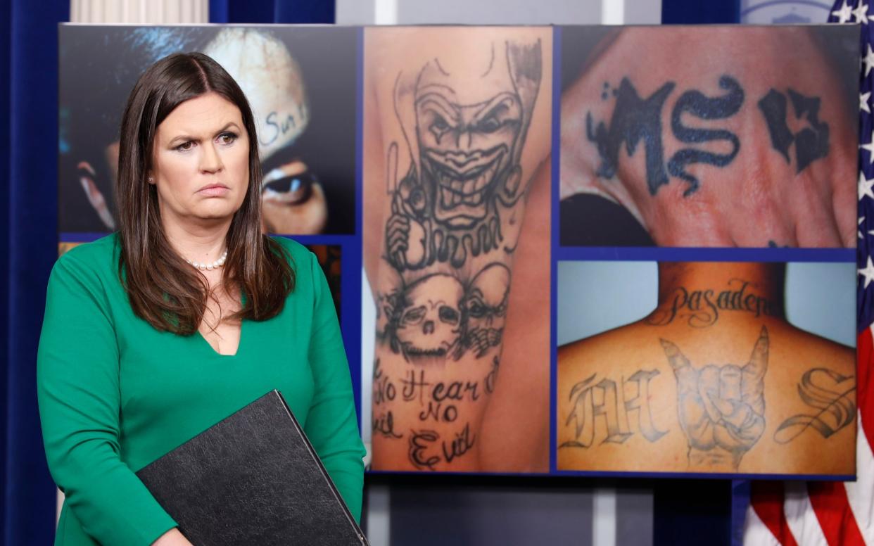 White House press secretary Sarah Huckabee Sanders stands in front of pictures of MS-13 gang tattoos during a press briefing at the White House in Washington, Thursday, July 27, 2017 - AP