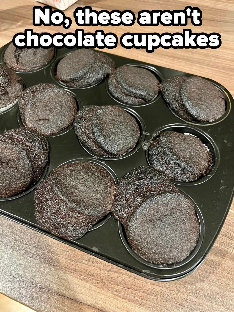 Burnt cupcakes in a pan, with caption, "No, these aren't chocolate cupcakes"