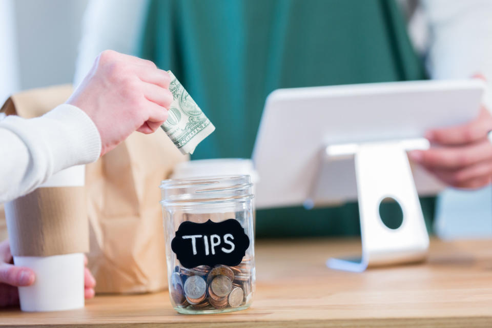 A customer putting money into a tip jar