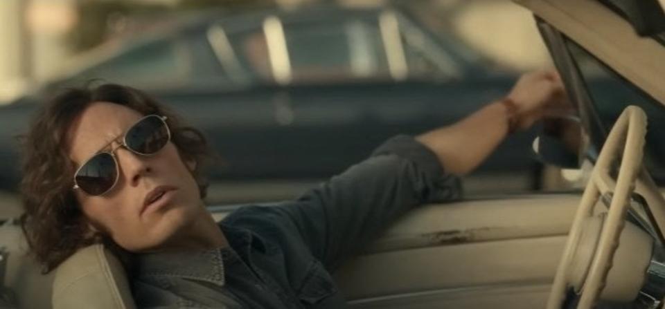 Sam Claflin as Billy Dunne, leaning back in the driver's seat of a parked car, wearing sunglasses